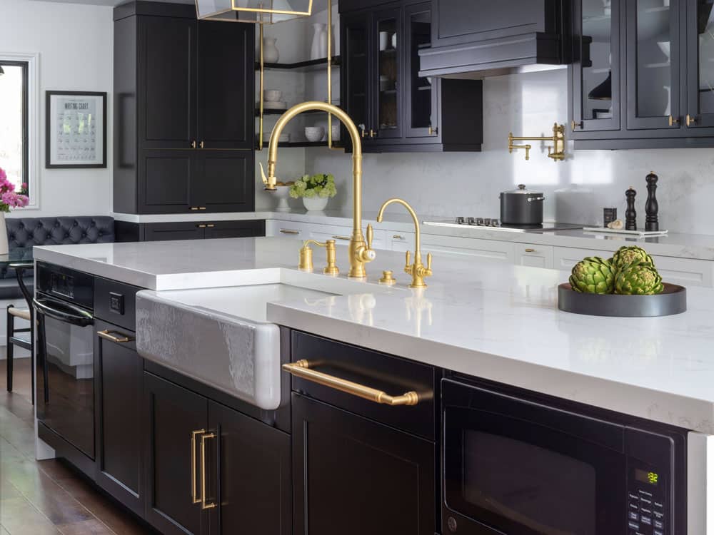 Modern kitchen with black cabinets and gold fixtures.