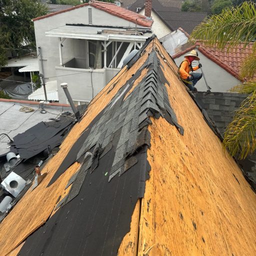 Worker repairing damaged house roof shingles.